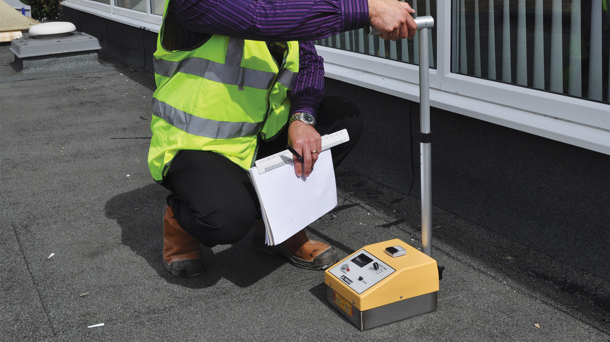 Roof surveyor checking a commercial flat roof for moisture before replacement